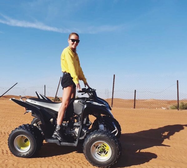Woman in the desert standing on the quad bike